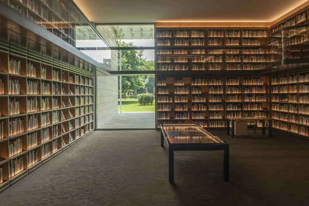 Sala de leitura com estantes de livros e uma ampla janela voltada para o jardim